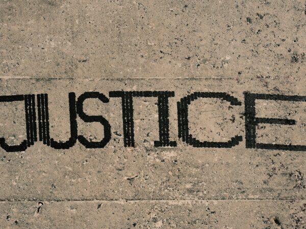 the word justice written in black ink on a concrete surface