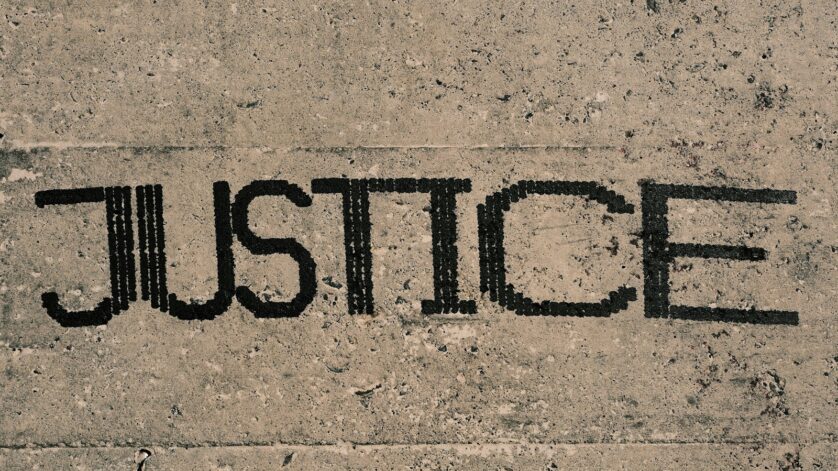 the word justice written in black ink on a concrete surface